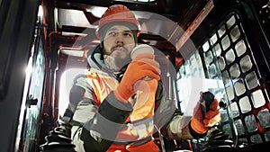 Forklift driver in protective vest driving forklift at warehouse of freight forwarding company. Man on the forklift