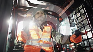 Forklift driver in protective vest driving forklift at warehouse of freight forwarding company. Man on the forklift