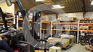 Forklift driver in protective vest driving forklift at warehouse of freight forwarding company. Man on the forklift