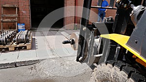 Forklift driver in protective vest driving forklift at warehouse of freight forwarding company. Man on the forklift