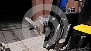 Forklift driver in protective vest driving forklift at warehouse of freight forwarding company. Man on the forklift