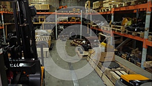Forklift driver in protective vest driving forklift at warehouse of freight forwarding company. Man on the forklift
