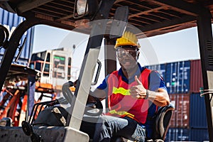 Forklift driver showing thumbs up, Worker man in hardhat and safety vest sitting in container stackers