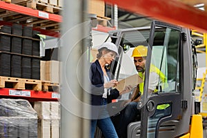 Forklift driver talking with manager in modern industrial factory. Warehouseman reading order, order picking. Warehouse