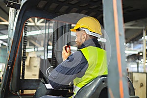Forklift driver talking on radio for professional cargo shipping communication