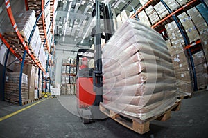 Forklift driver transporting sacks in warehouse