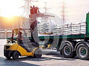 Forklift handling white sugar bags outside warehouse for stuffing onto truck.