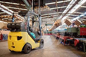 The forklift is in a large and light warehouse. Yellow color