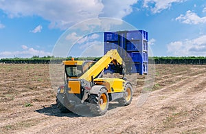 Forklift loader loads plastic containers outdoor.