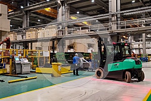 A forklift is loading steel sheets into a production pressing line in an automotive factory