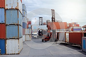 Forklift loading and unloading goods, container boxes in a shipping yard with containers stacked behind them