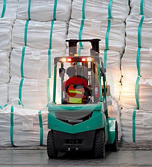 Forklift operation in warehouse, lifting cargo in jumbo bag into stack.
