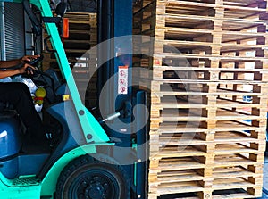 Forklift operator handling wooden pallets in warehouse cargo for transportation to customer factory