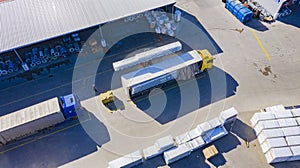 Forklift is putting cargo from warehouse to truck outdoors. Aerial. top view
