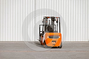 Forklift, reliable heavy loader parked next to the gates of hangar