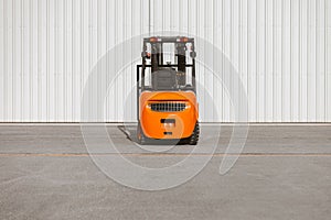 Forklift, reliable heavy loader parked next to the gates of hangar. Industrial vehicle