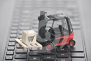 Forklift with shopping cart graphic on wooden block over laptop keyboard