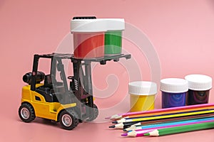 A forklift truck holds jars of gouache on a platform and loads them onto a stack from below. The concept of logistics and delivery