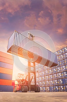 Forklift truck lifting cargo container in shipping yard