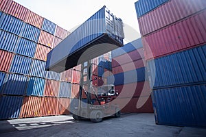 Forklift truck lifting cargo container in shipping yard or dock yard against sunrise sky for transportation import