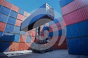 Forklift truck lifting cargo container in shipping yard or dock yard against sunrise sky for transportation import