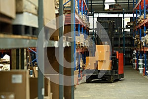 Forklift truck parking in large logistic distribution warehouse full of shelves with cardboard boxes