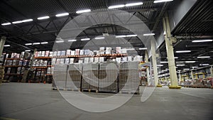 Forklift trucks move inside warehouse building. Creative. Large metal shelves at a modern warehouse and pallets with