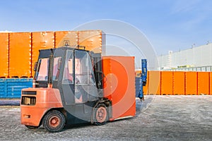 Forklift unloading truck semi trailer with wrapped cardboard boxes outdoors. openair warehouse works background
