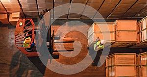 Forklift with worker in operation in storage warehouse to move pallets