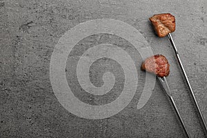 Forks with fried meat fondue pieces on grey background