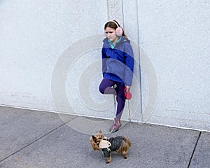 Forlorn-looking little girl leaning on wall while holding tiny Yorkshire Terrier dog on leash photo