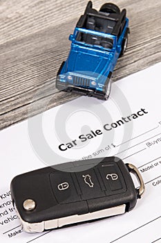 Form of car sale agreement, blue toy car and key. Sales, purchases new or used vehicle
