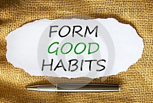 Form good habits symbol. Words `Form good habits` on white paper. Black metallic pen. Beautiful canvas background. Business,