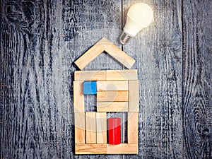 Form of house above tree on dark wooden background and LED bulb. Imitation of heating copper or boiler and air conditioner