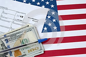 Form 1099-misc Miscellaneous income and blue pen with dollar bills lies on United States flag. Internal revenue service tax form photo