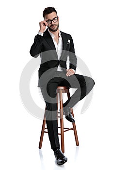 Formal business man sitting and fixing glasses