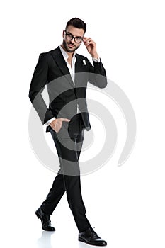 Formal businessman walking with hand in pocket fixing glasses