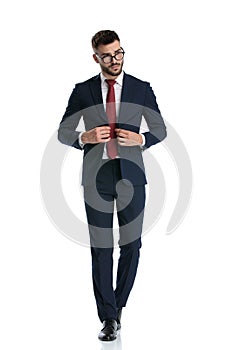 Formal man walking while closing jacket and posing cool