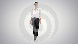 Formal young woman walking and smiling on gradient background.