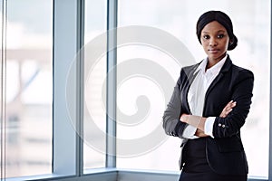 Formally dressed blackbusiness woman looking at camera with arms crossed