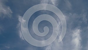 Formation and rapid movement of white clouds of different shapes in the blue sky in late spring at sunset.