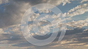 Formation and rapid movement of white clouds of different shapes in the blue sky in late spring at sunset.