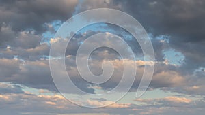 Formation and rapid movement of white clouds of different shapes in the blue sky in late spring at sunset.