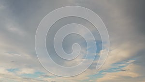 Formation and rapid movement of white clouds of different shapes in the blue sky in late spring at sunset.