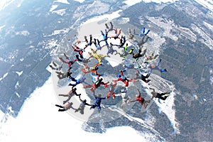 A formation of skydivers is in the winter sky.