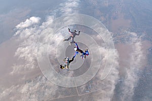 Formation skydiving. Three skydivers are in the sky.