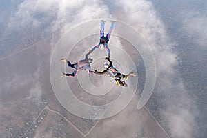Formation skydiving. Three skydivers are in the sky.