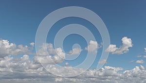 Formation of soft silver clouds float across blue sky, panorama format
