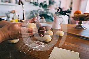 Forming dough balls for baking buns on the wooden table.