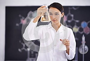 The formula is complete. a female scientist observing liquid in a conical beaker.